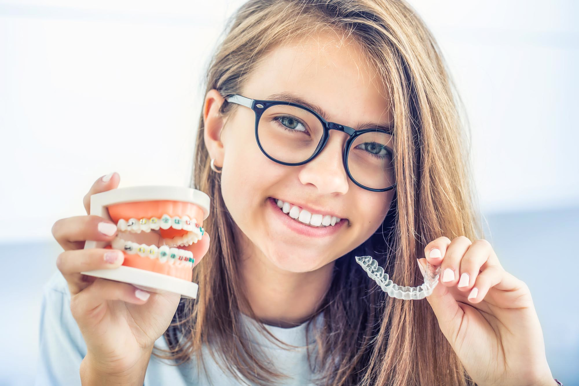 Jente viser Invisalign med tannmodell